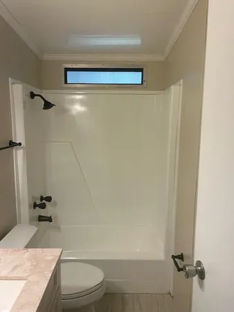a bathroom with a granite countertop bathtub shower sink vanity and toilet