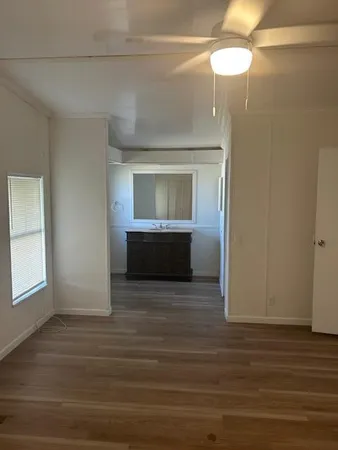 a view of empty room with wooden floor and fan
