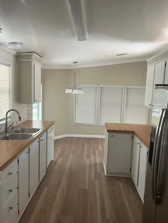 a kitchen with granite countertop a sink a refrigerator and wooden floor