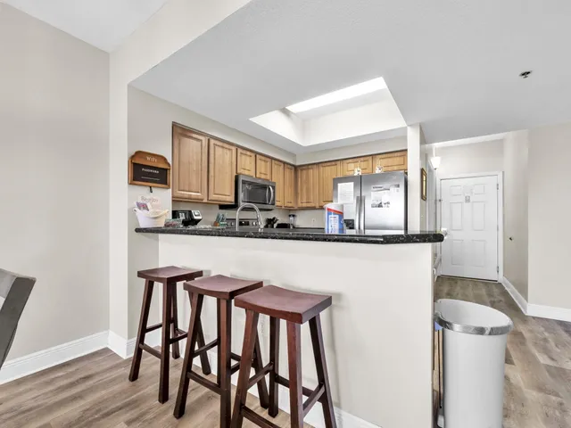 a kitchen with stainless steel appliances a white refrigerator a stove a microwave oven a sink and dishwasher with wooden floor