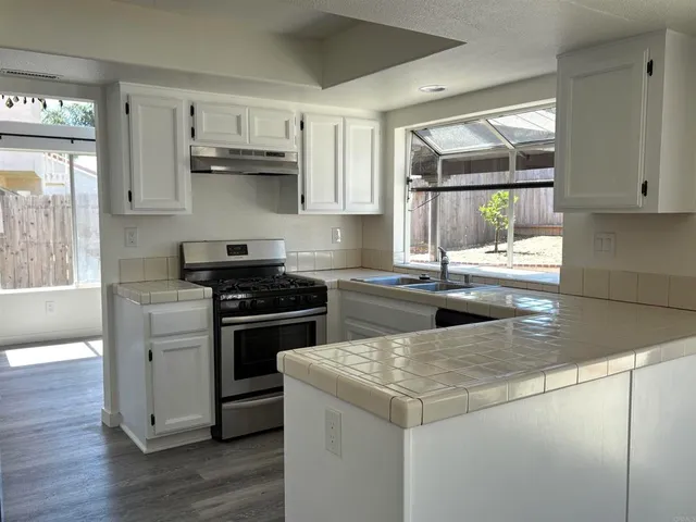 a kitchen with stainless steel appliances granite countertop a stove a sink and a microwave