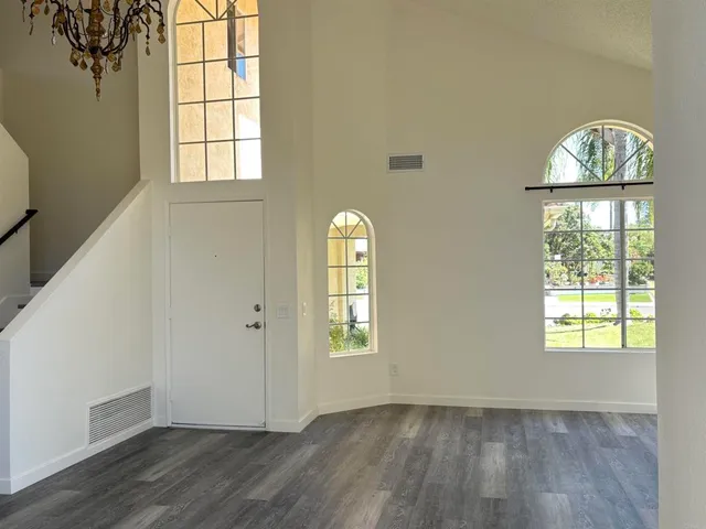 an empty room with wooden floor windows and entryway
