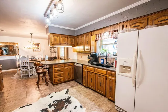 a kitchen with stainless steel appliances granite countertop a refrigerator a sink dishwasher a stove and white countertops with wooden floor