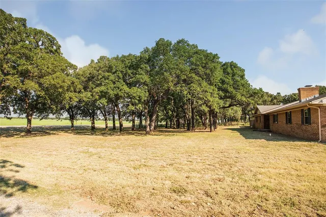 a tall yellow house with trees in the background