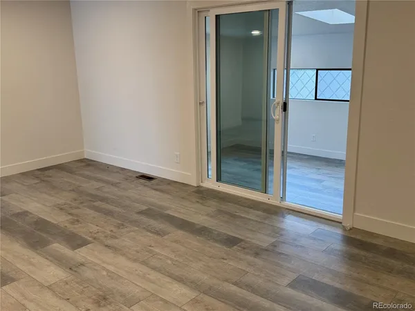 an empty room with wooden floor and mirror