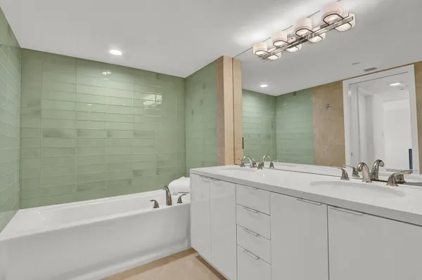 a bathroom with a double vanity sink mirror and bathtub