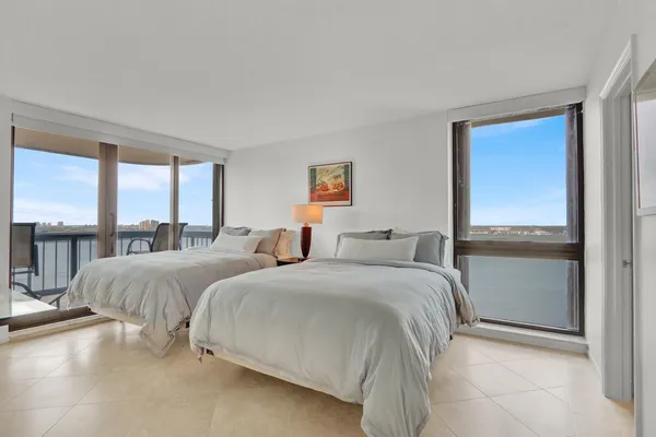 a bedroom with two beds and large windows