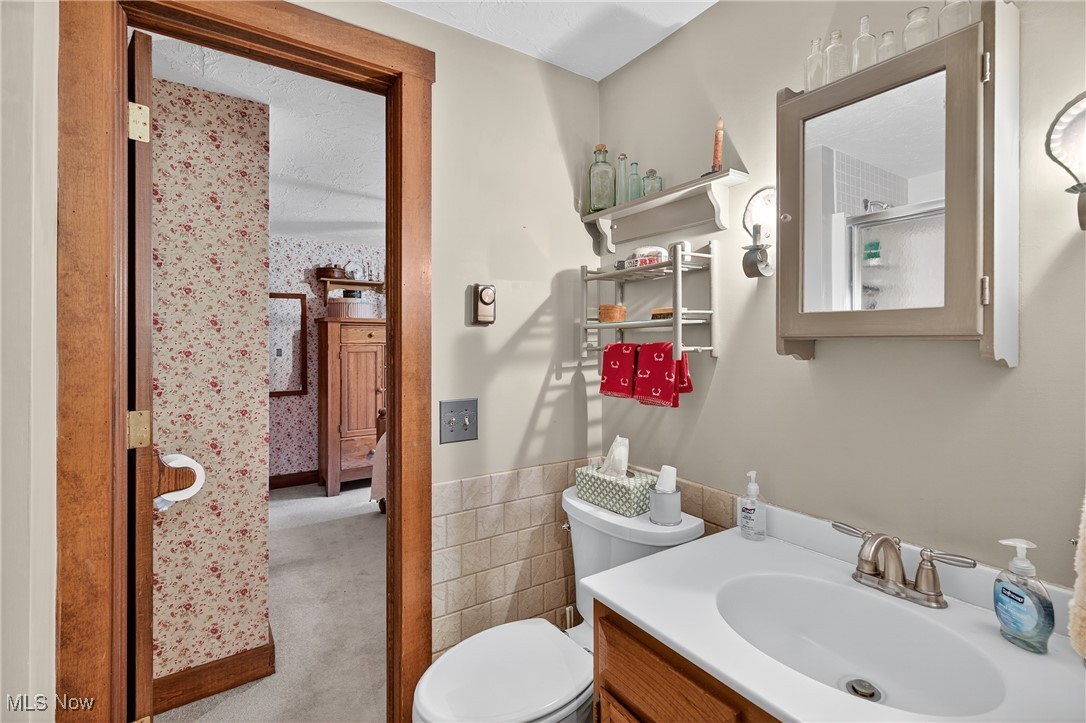 25700 Winona Road Homeworth, OH 44634 - Photo 27 of 49 Full bathroom featuring tile walls, vanity, and a wainscoted wall