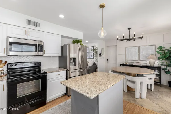 a kitchen with stainless steel appliances kitchen island granite countertop a stove refrigerator and microwave