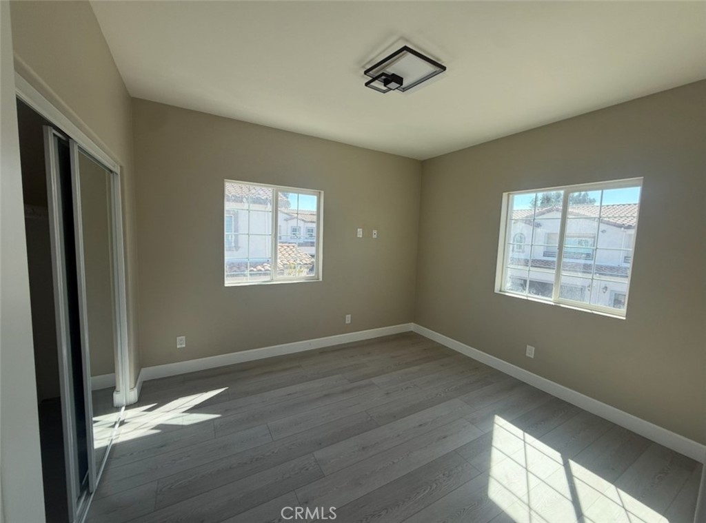 15909 Merrill Avenue, Unit 10 Fontana, CA 92335 - Photo 10 of 14 a view of an empty room with wooden floor and a window