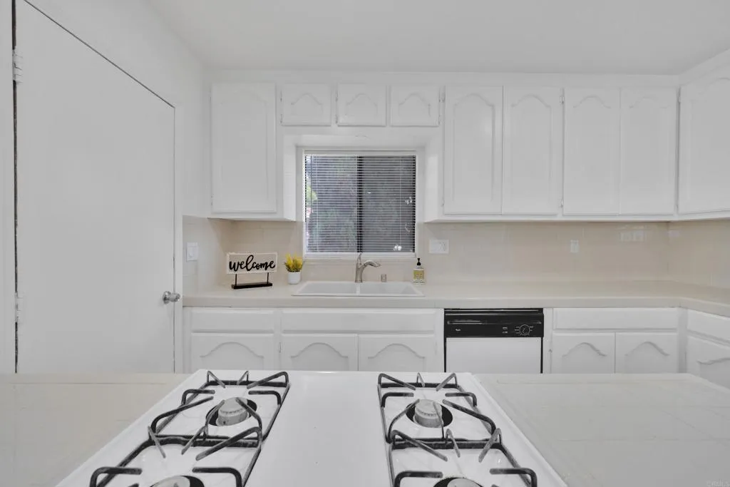 9015 Campo Road Spring Valley, CA 91977 - Photo 17 of 58 a kitchen with a white stove top oven and white cabinets