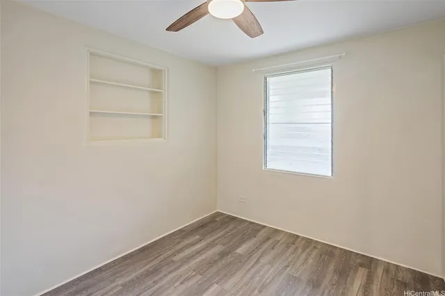 an empty room with a window and ceiling fan