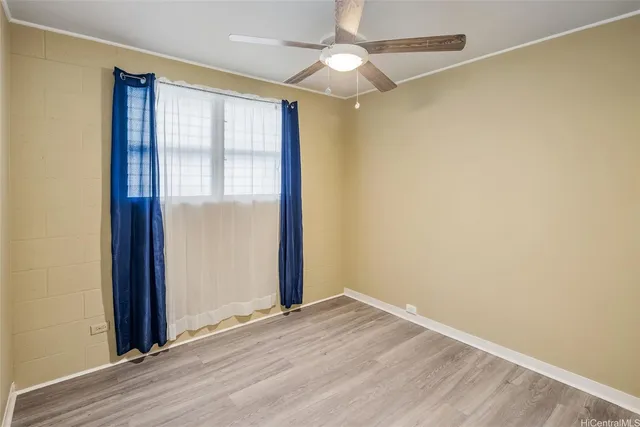 an empty room with wooden floor fan and windows