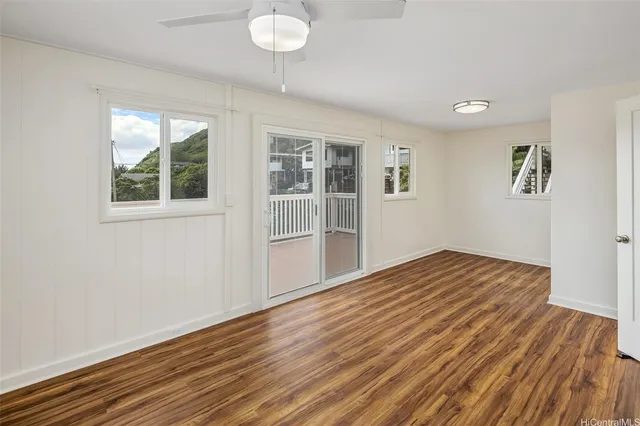 a view of empty room with wooden floor and fan