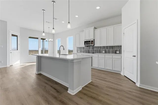 an empty room with wooden floor fireplace and windows