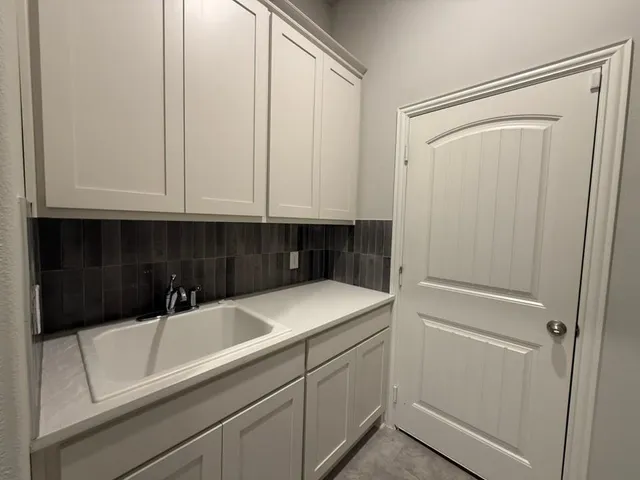 a large kitchen with kitchen island a sink dishwasher a stove a refrigerator and white cabinets with wooden floor