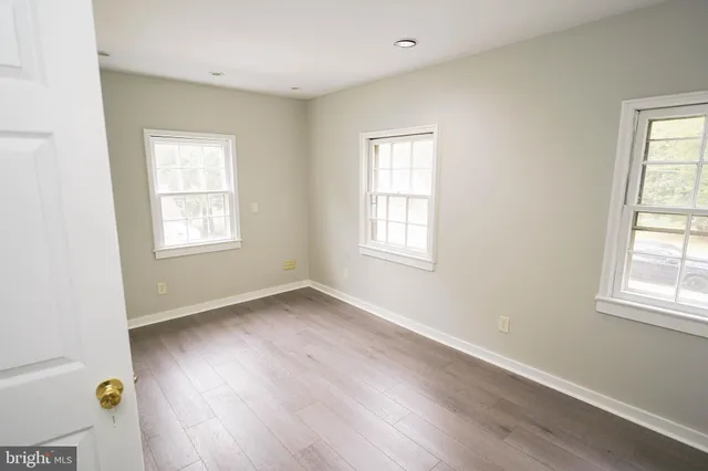 an empty room with wooden floor and fan