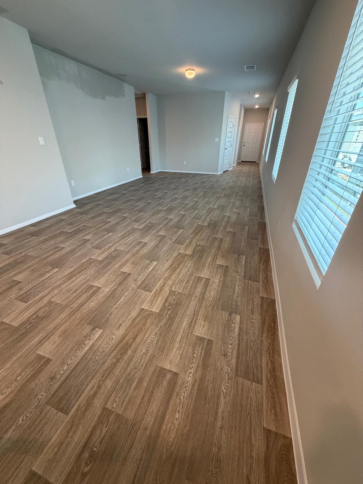 2701 Towy Road Manor, TX 78653 - Photo 7 of 35 Long plank flooring graces this welcoming living space, leading to a well-lit hallway.
