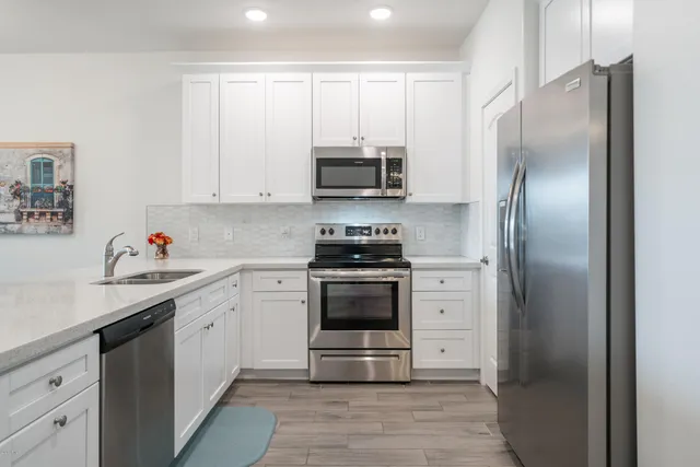 a kitchen with white cabinets and stainless steel appliances