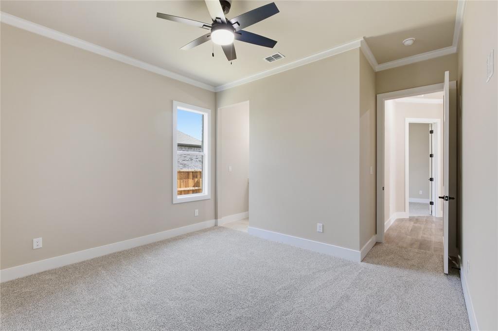 709 Anne Road Van Alstyne, TX 75495 - Photo 12 of 28 Spacious room with light neutral wall tones, plush gray carpeting, and crisp white baseboards and crown molding