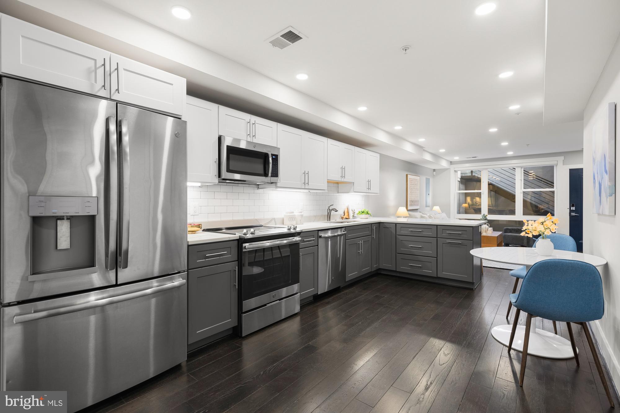 1503 K Street Southeast, Unit C01 Washington, DC 20003 - Photo 7 of 16 a kitchen with stainless steel appliances a refrigerator a stove a sink dishwasher a dining table and chairs with wooden floor