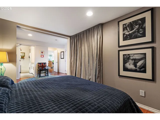 a large bedroom with bed and paintings on wall