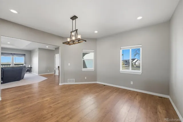 a kitchen with stainless steel appliances granite countertop a refrigerator a sink dishwasher a stove and a dining table with wooden floor