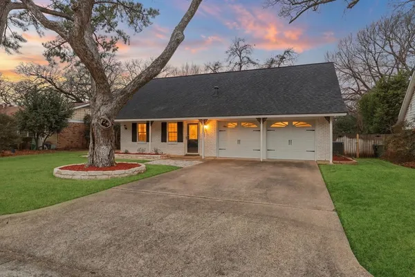 front view of a house with a yard garage and trees