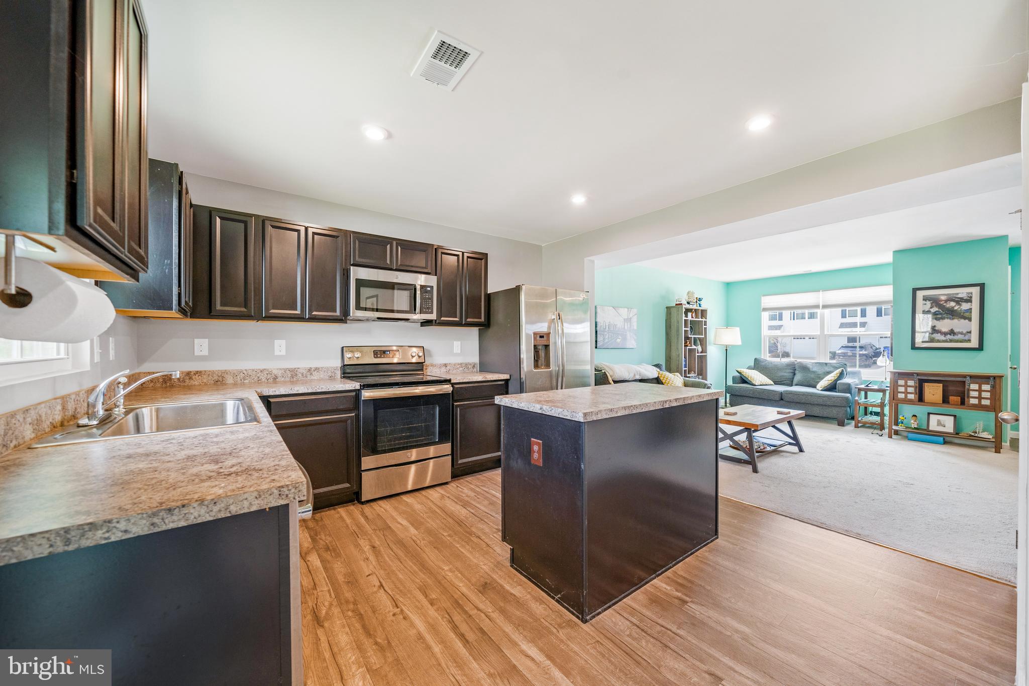 141 Wye Oak Drive Townsend, DE 19734 - Photo 8 of 32 a kitchen with stainless steel appliances granite countertop a stove top oven a sink dishwasher a dining table and chairs with wooden floor