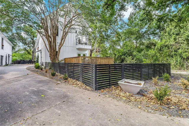a backyard of a house with wooden fence and large trees