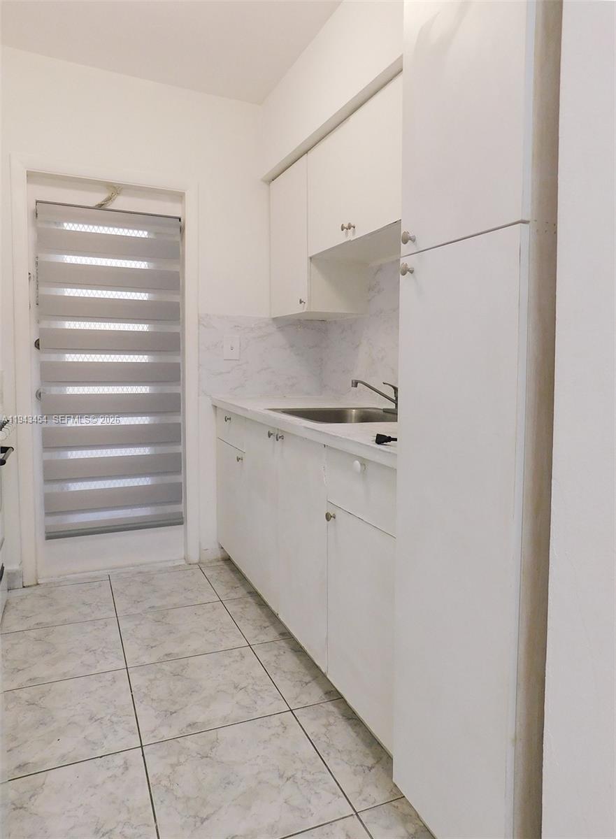 7840 Harding Avenue, Unit 2 Miami Beach, FL 33141 - Photo 11 of 19 a kitchen with white cabinets and a sink