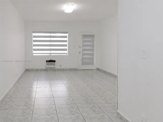 an empty room with a white cabinet and a window