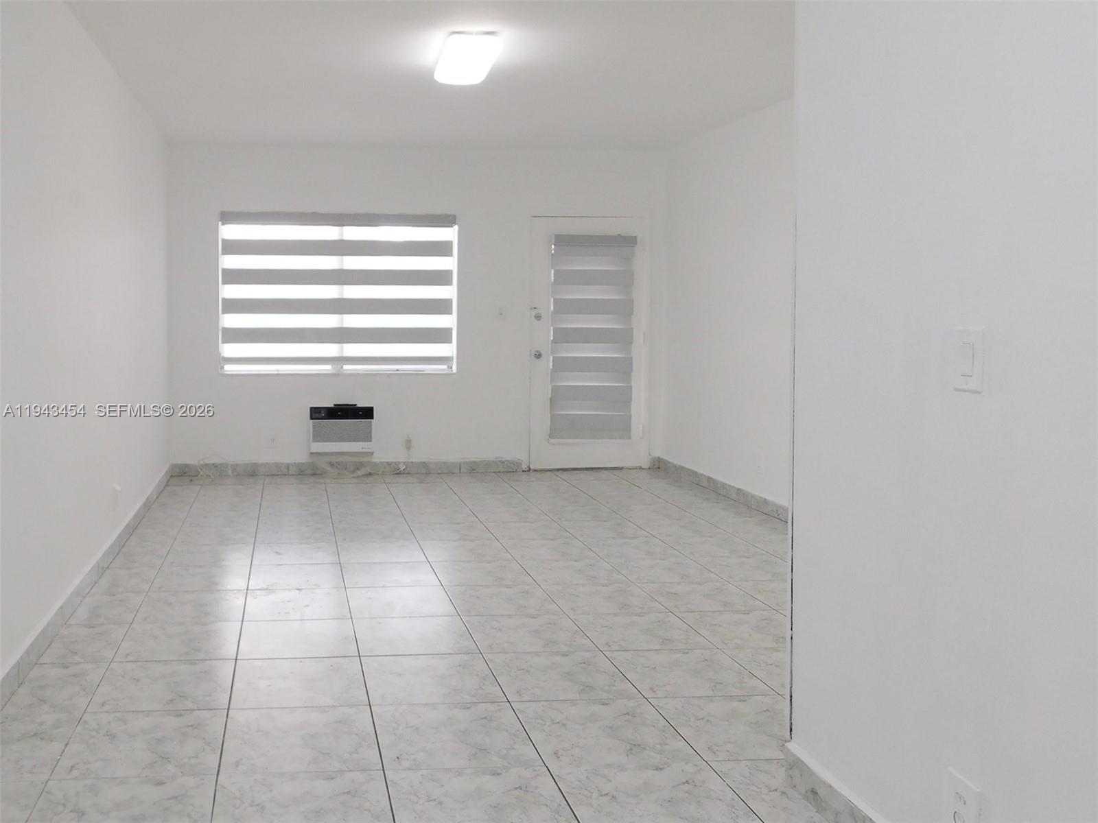 7840 Harding Avenue, Unit 2 Miami Beach, FL 33141 - Photo 6 of 19 an empty room with a white cabinet and a window