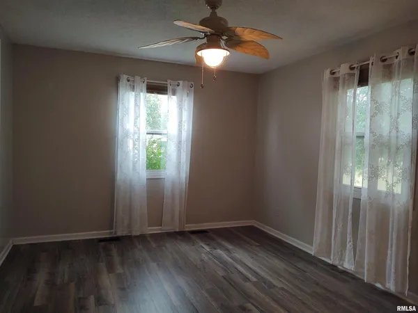 a view of an empty room with window wooden floor and cabinet