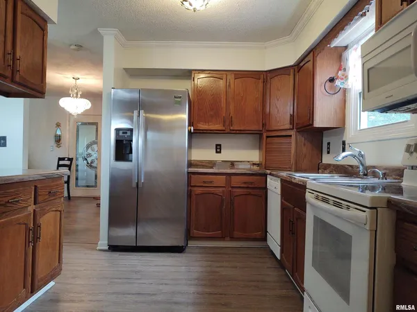 a kitchen with stainless steel appliances granite countertop a refrigerator a sink dishwasher a stove with wooden cabinets and floor