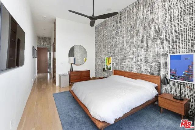 a bedroom with a bed a dresser and potted plants with the wooden floor