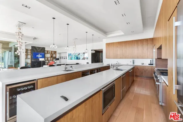 a dining hall with stainless steel appliances kitchen island granite countertop a table chairs and a view of living room