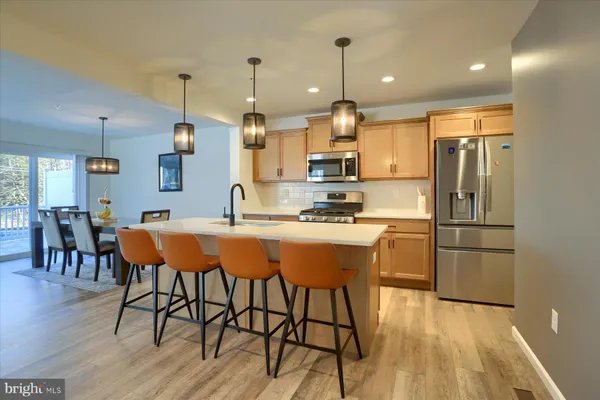 a kitchen with stainless steel appliances kitchen island granite countertop a refrigerator a stove a sink with a dining table and chairs