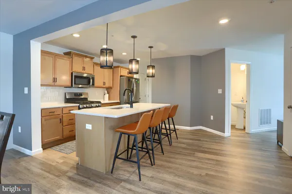 a kitchen with stainless steel appliances kitchen island granite countertop a table chairs and a refrigerator