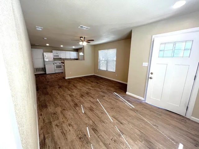 an empty room with wooden floor and windows
