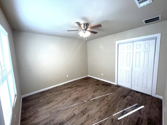 an empty room with windows and fan