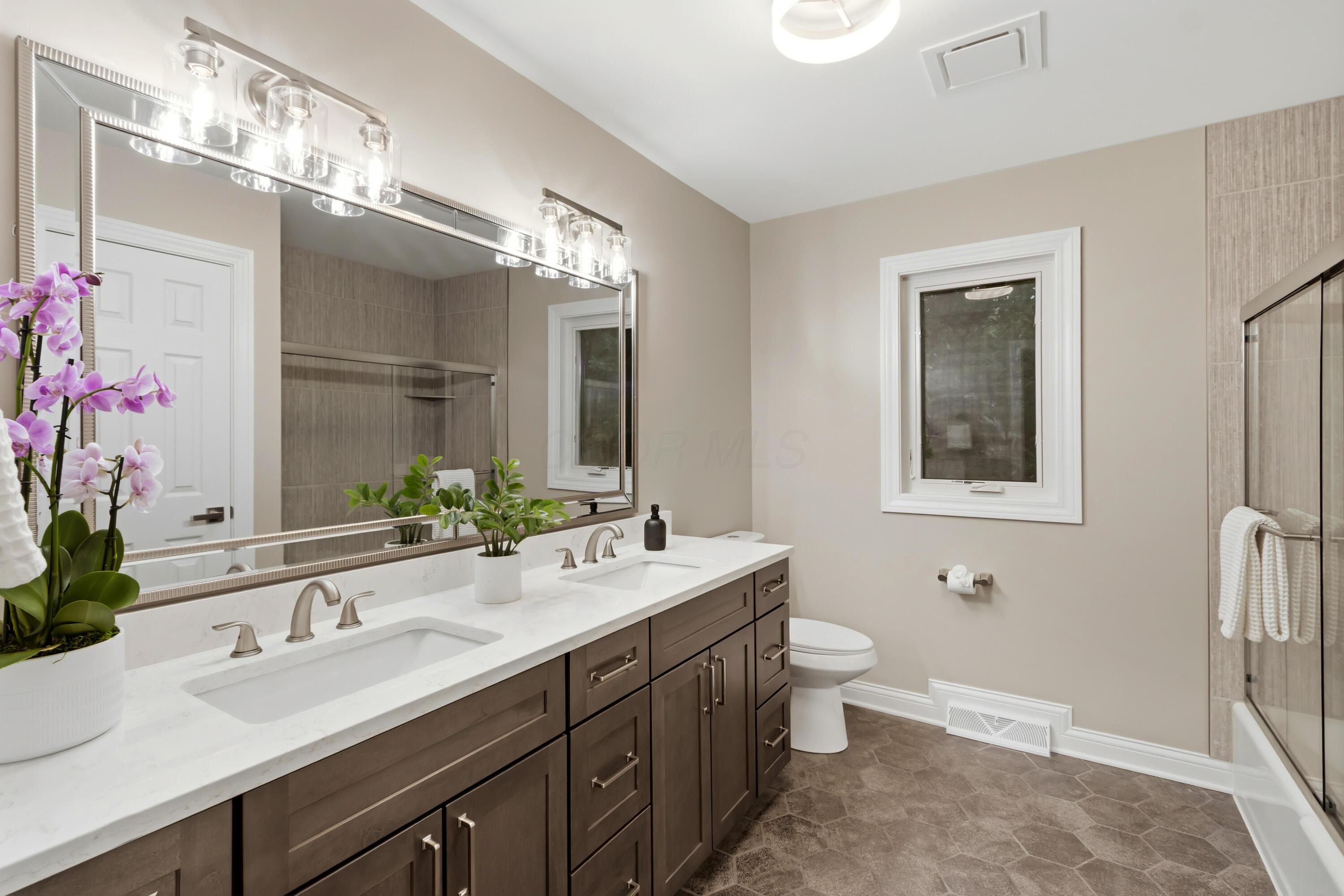 1560 Carriage Road Powell, OH 43065 - Photo 44 of 73 Dual vanity with undermount sinks and brushed nickel fixtures, large framed mirror, and a glass-enclosed tub/shower