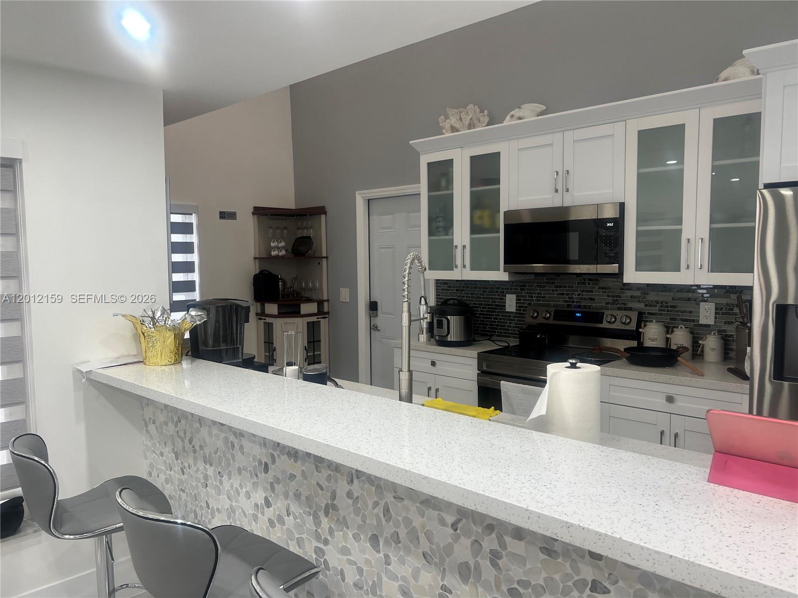 13595 Southwest 99th Street Miami, FL 33186 - Photo 19 of 44 a kitchen with stainless steel appliances kitchen island granite countertop a sink and a microwave