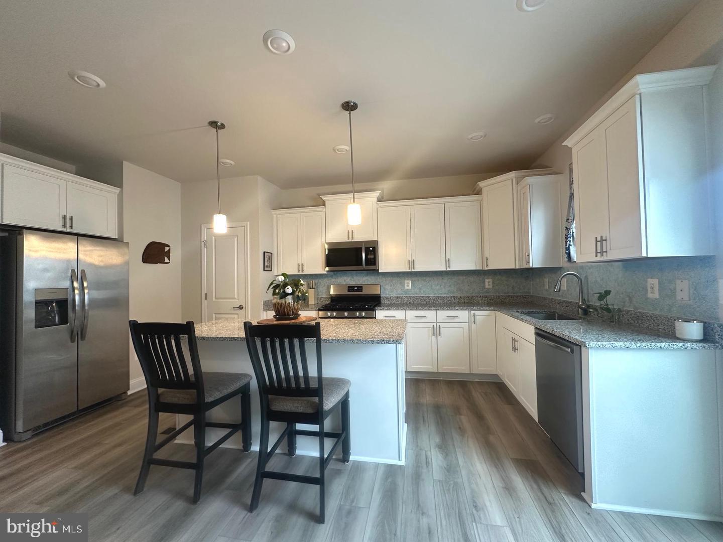 35393 Wright Way Millsboro, DE 19966 - Photo 7 of 28 a kitchen with a dining table chairs refrigerator and cabinets