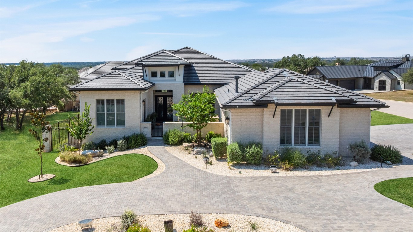 View of front of home featuring brick siding, decorative driveway, and a tile roof
