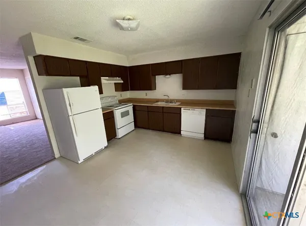 a kitchen with a sink a stove top oven and cabinetry