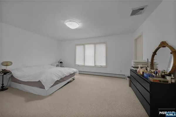 a spacious bedroom with a bed and a dresser