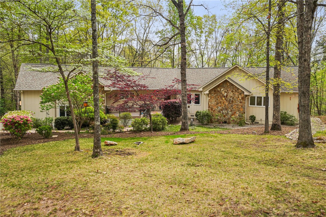A charming residence featuring stone accents and a spacious front yard, offering a tranquil retreat.