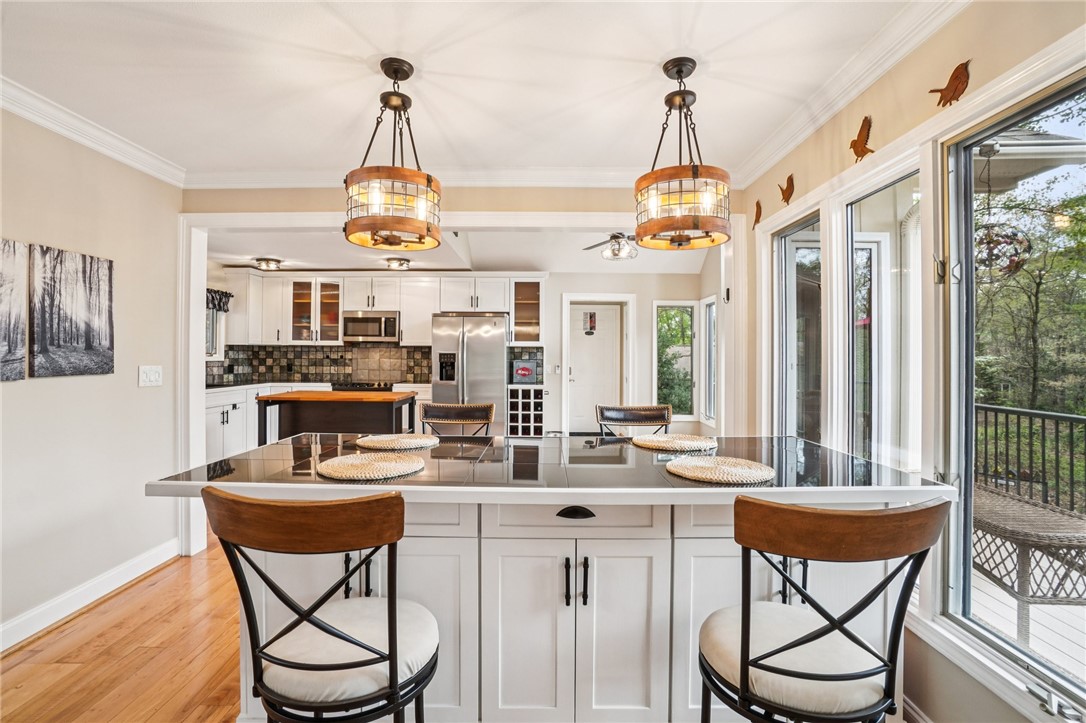120 Beacon Ridge Circle Salem, SC 29676 - Photo 18 of 49 This bright kitchen features rich wood flooring, modern light fixtures, and expansive windows showcasing lush greenery.