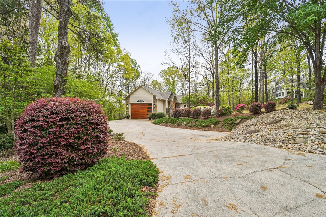 120 Beacon Ridge Circle Salem, SC 29676 - Photo 5 of 49 A spacious driveway leads to a charming residence nestled among lush trees and vibrant landscaping.